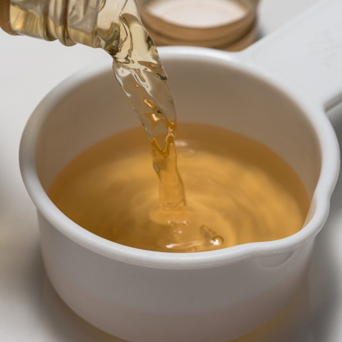 Pouring apple cider vinegar into a measuring cup
