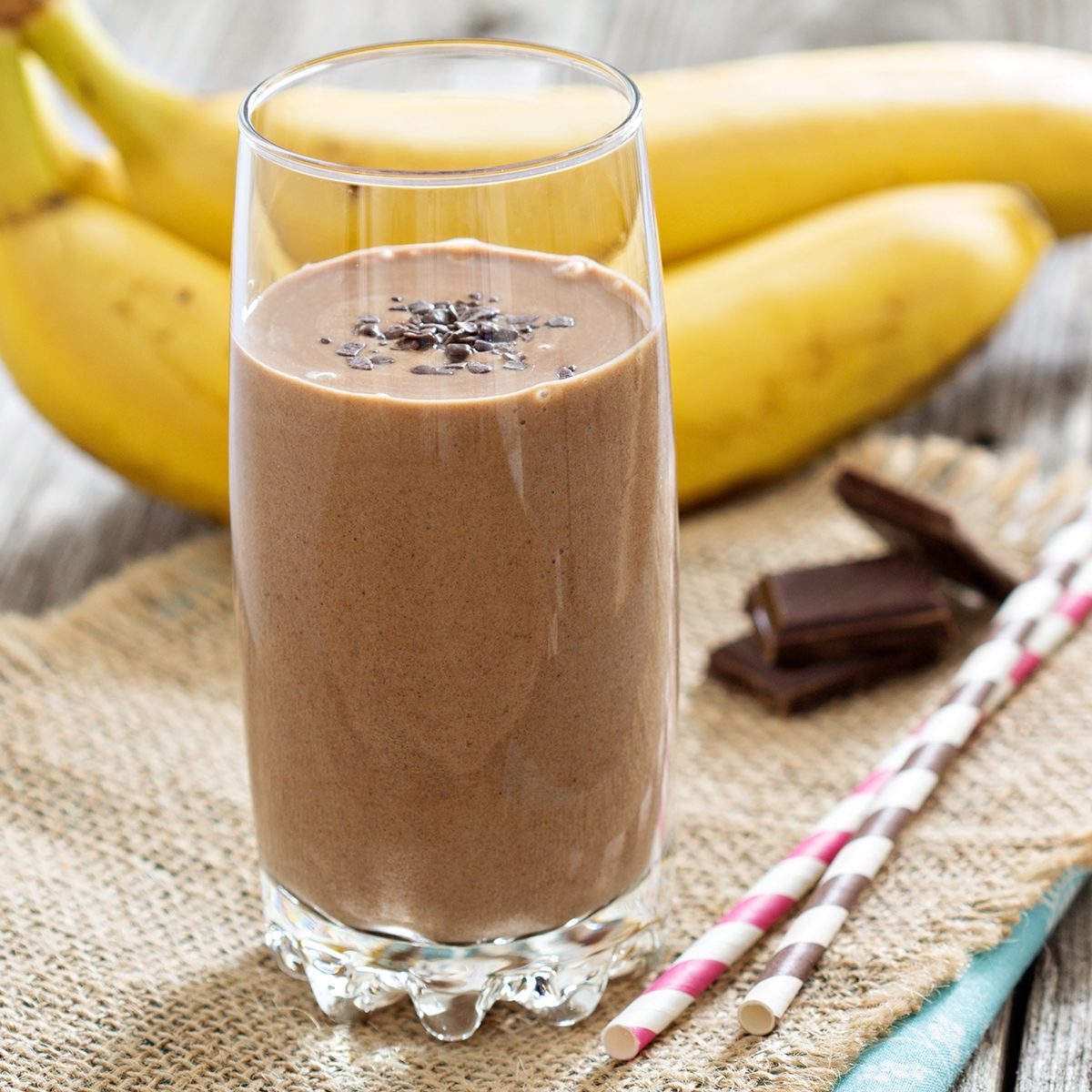 Chocolate banana smoothie in a glass with straws