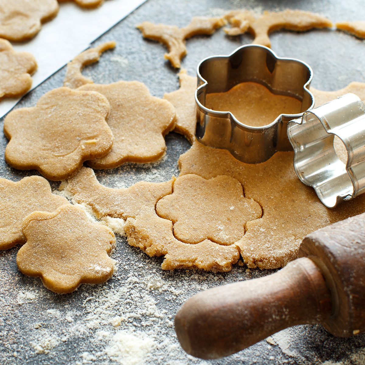Cooking cookies with cookie cutters on a dark table