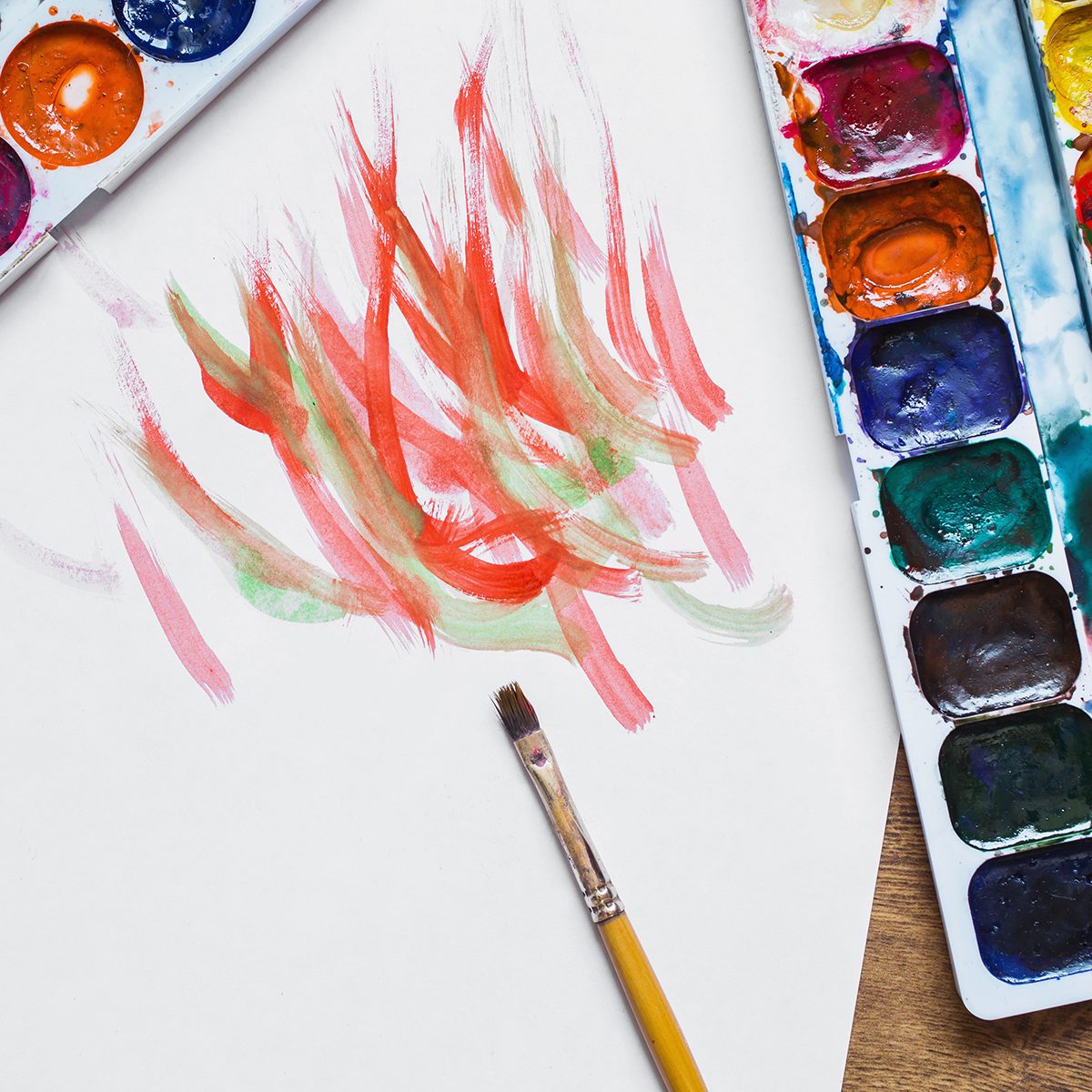 Artistic squirrel brushes, tubes of oil paints and watercolors on a wooden background.