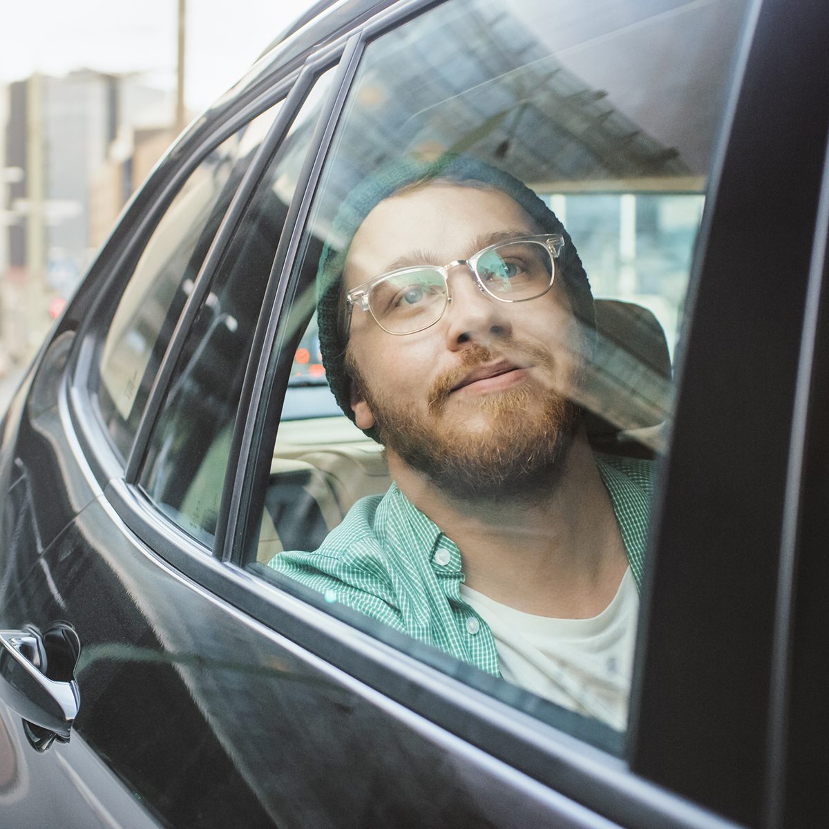 Stylish Young Man Rides on a Passenger Back Seat of a Car