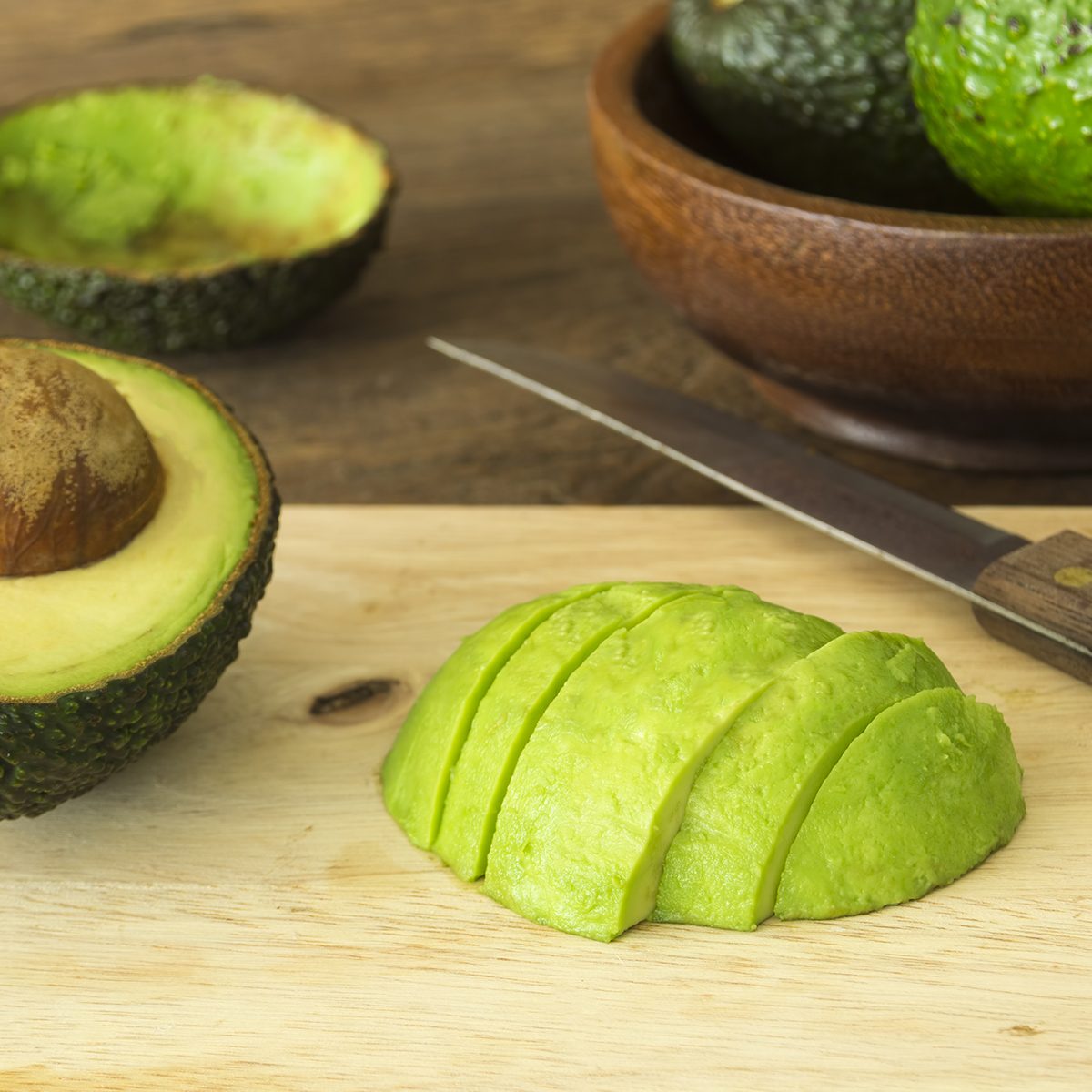 avocado and Sliced avocado slices on wooden board
