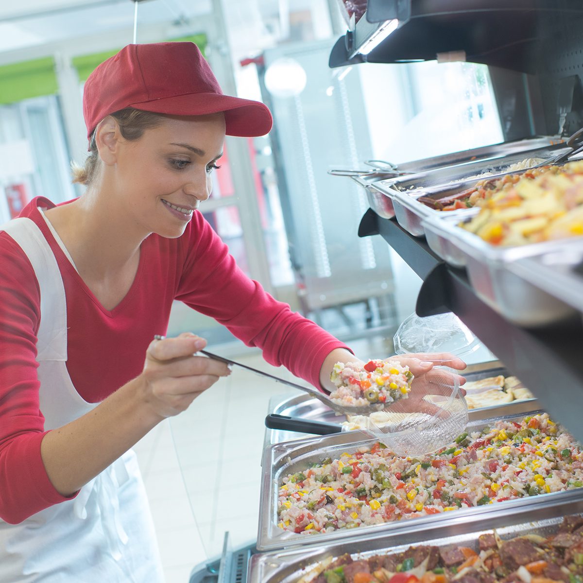 buffet female worker servicing food in cafeteria