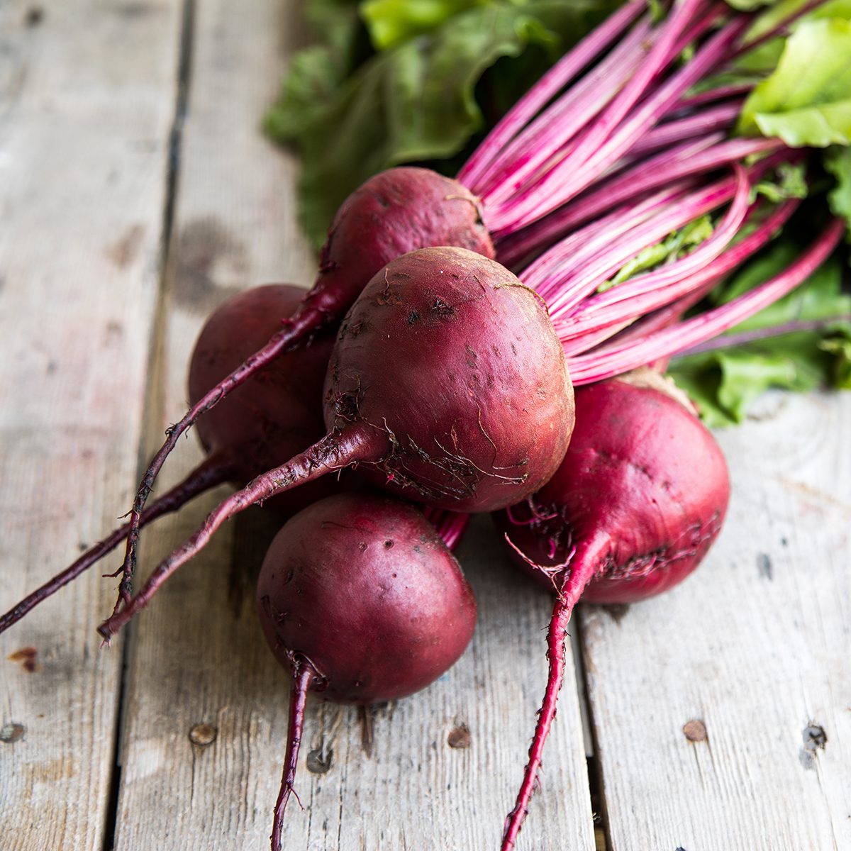 Red Beetroot with herbage green leaves on rustic background.