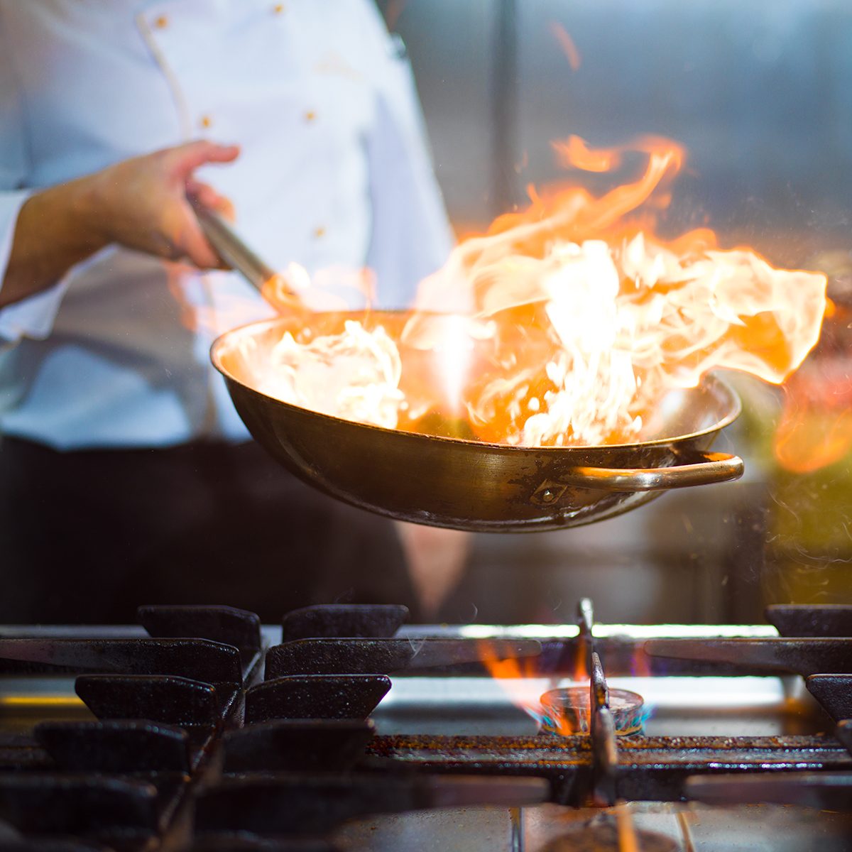 Chef cooking and doing flambe on food in restaurant kitchen