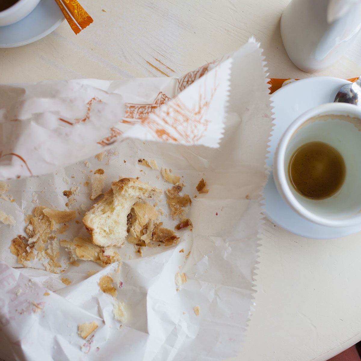 Empty coffee Cup and the remains of biscuits are on the table.