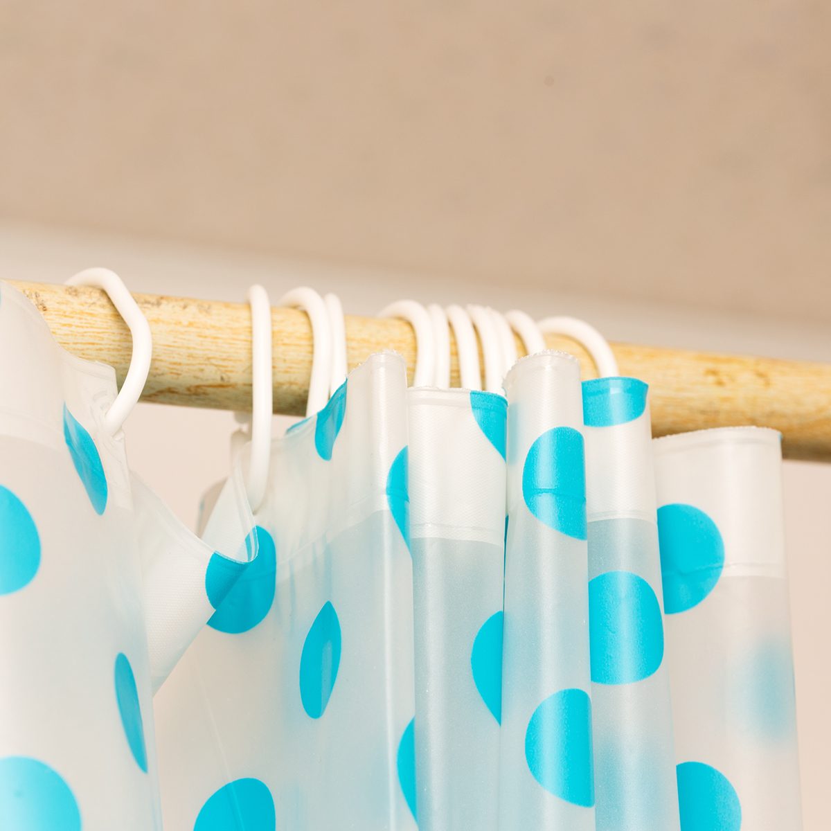 cream curtains hanging on the rope on the plastic hook in the white ceiling illuminated by daylight