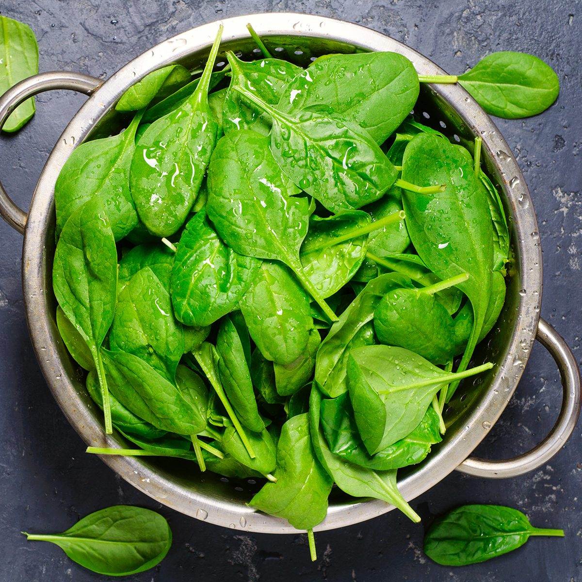 Washed fresh mini spinach in a colander on the old concrete table