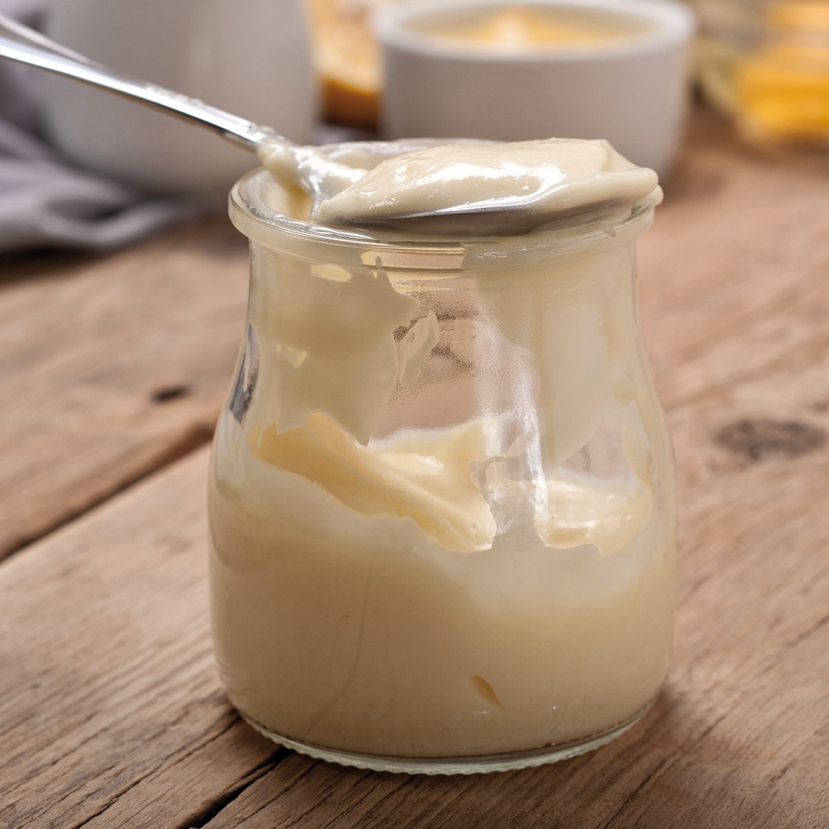 Homemade mayonnaise in glass jar closeup on a wooden table