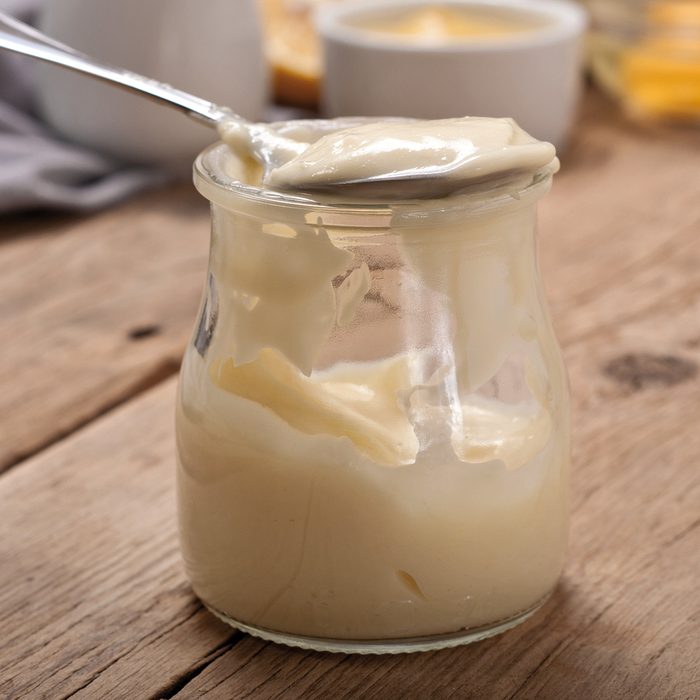 Homemade mayonnaise in glass jar closeup on a wooden table