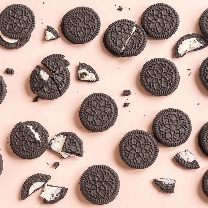 Chocolate and cream sandwich cookies on pink pastel background, top view.