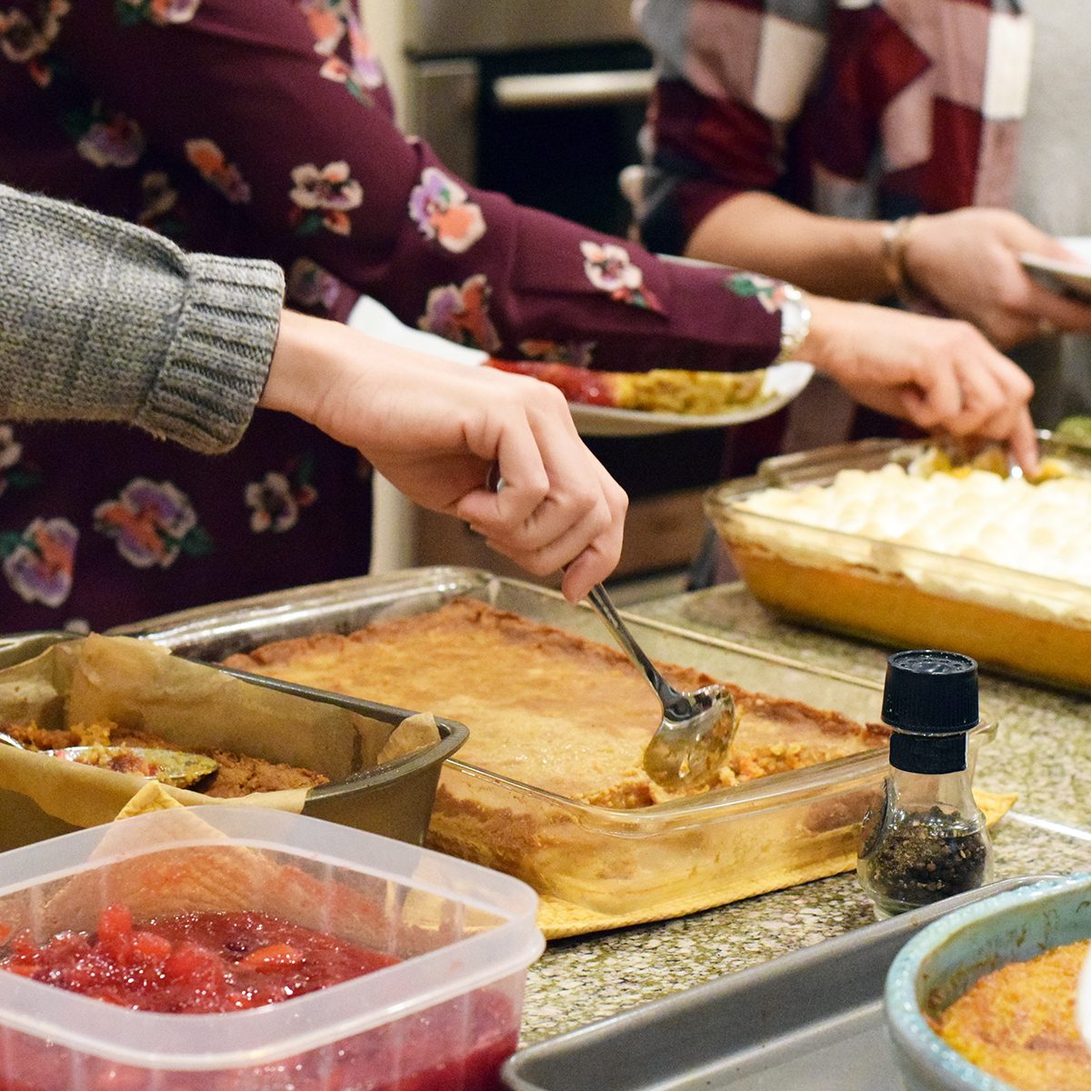People serving themselves Thanksgiving dinner from various different casseroles and pans