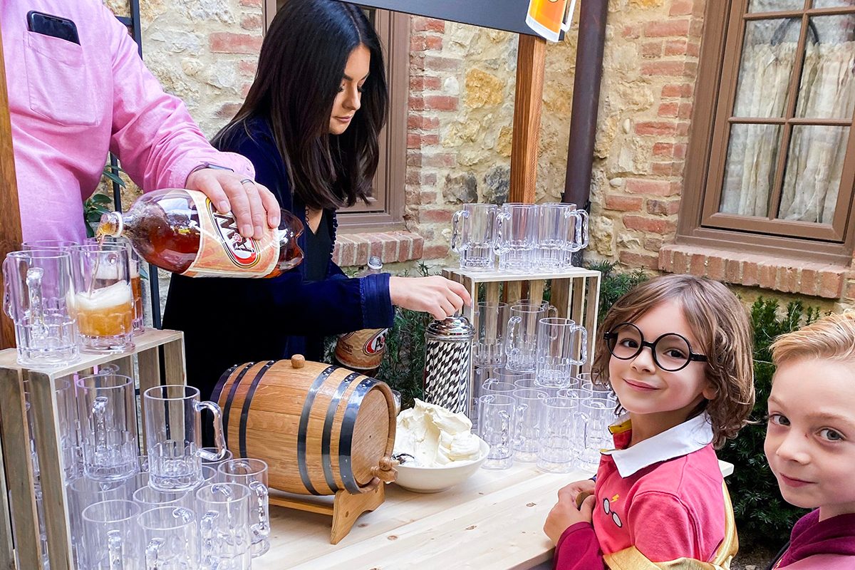 two children in harry potter outfits waiting in line for butter beer floats