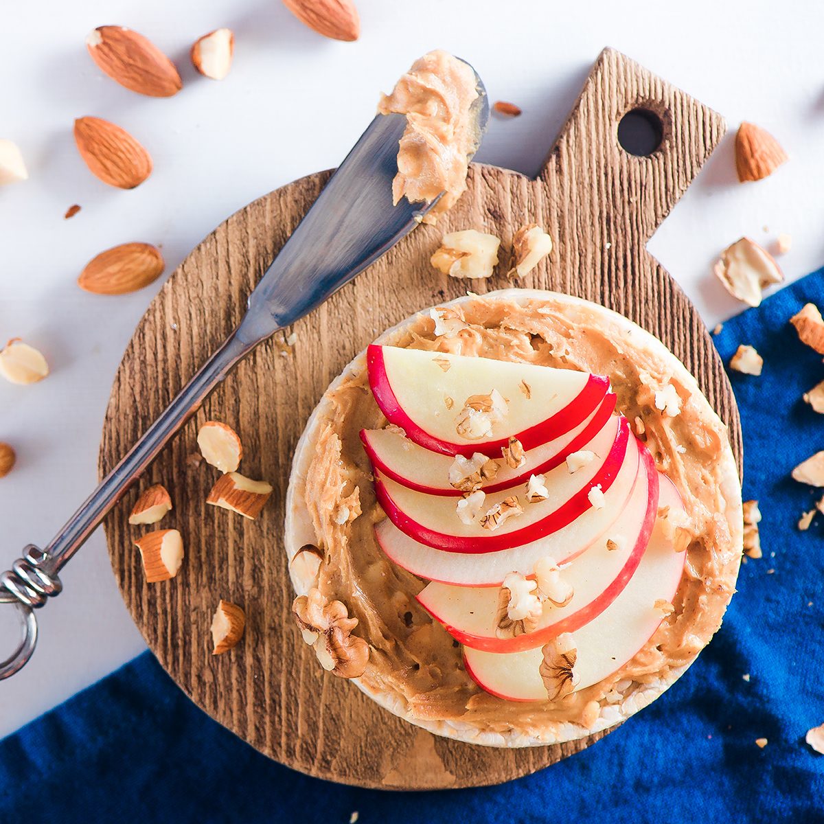 Apple crisp bread toast with apple slices, peanut butter, almonds and walnuts. Healthy breakfast concept in a high key.