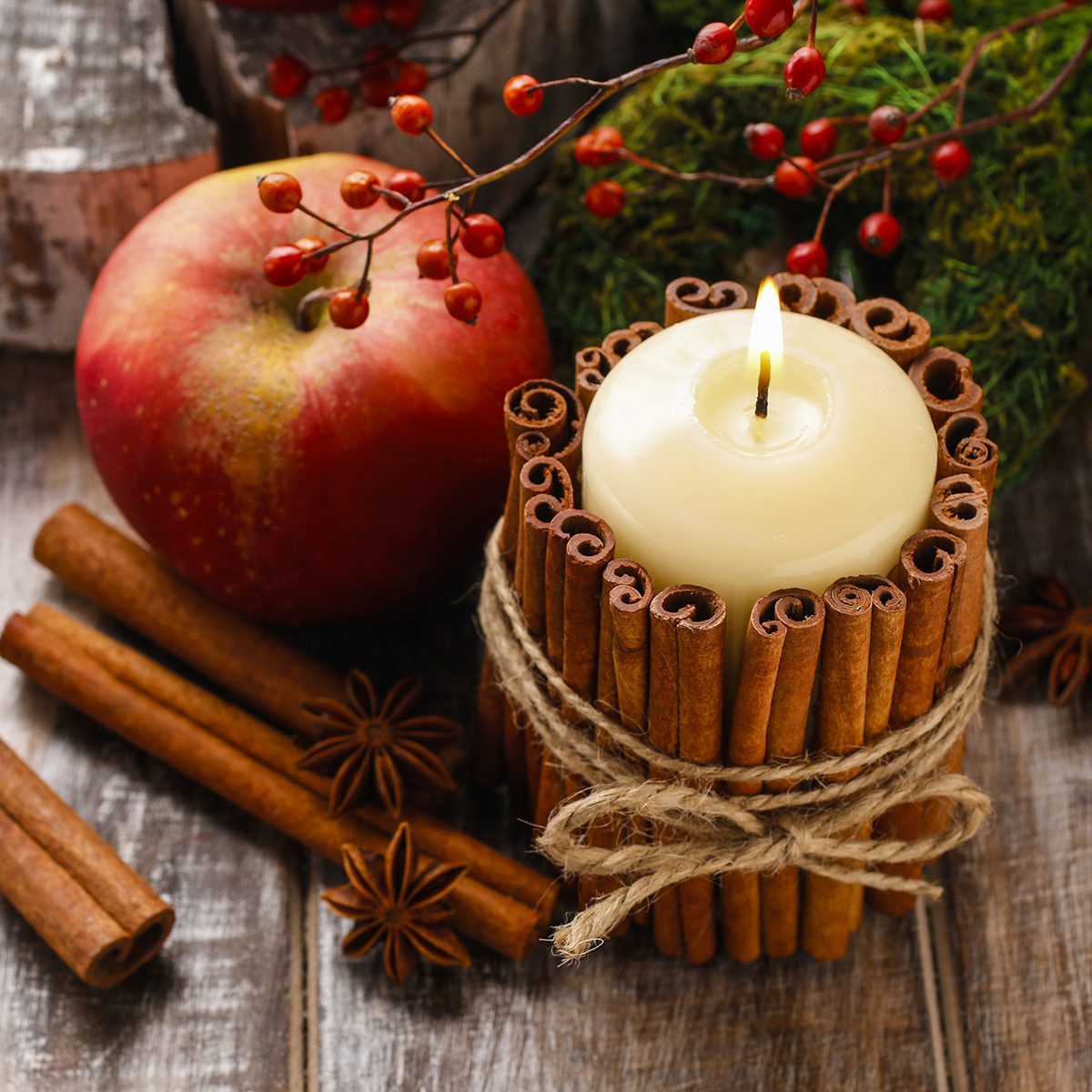 Candle decorated with cinnamon sticks and red apples, christmas decoration