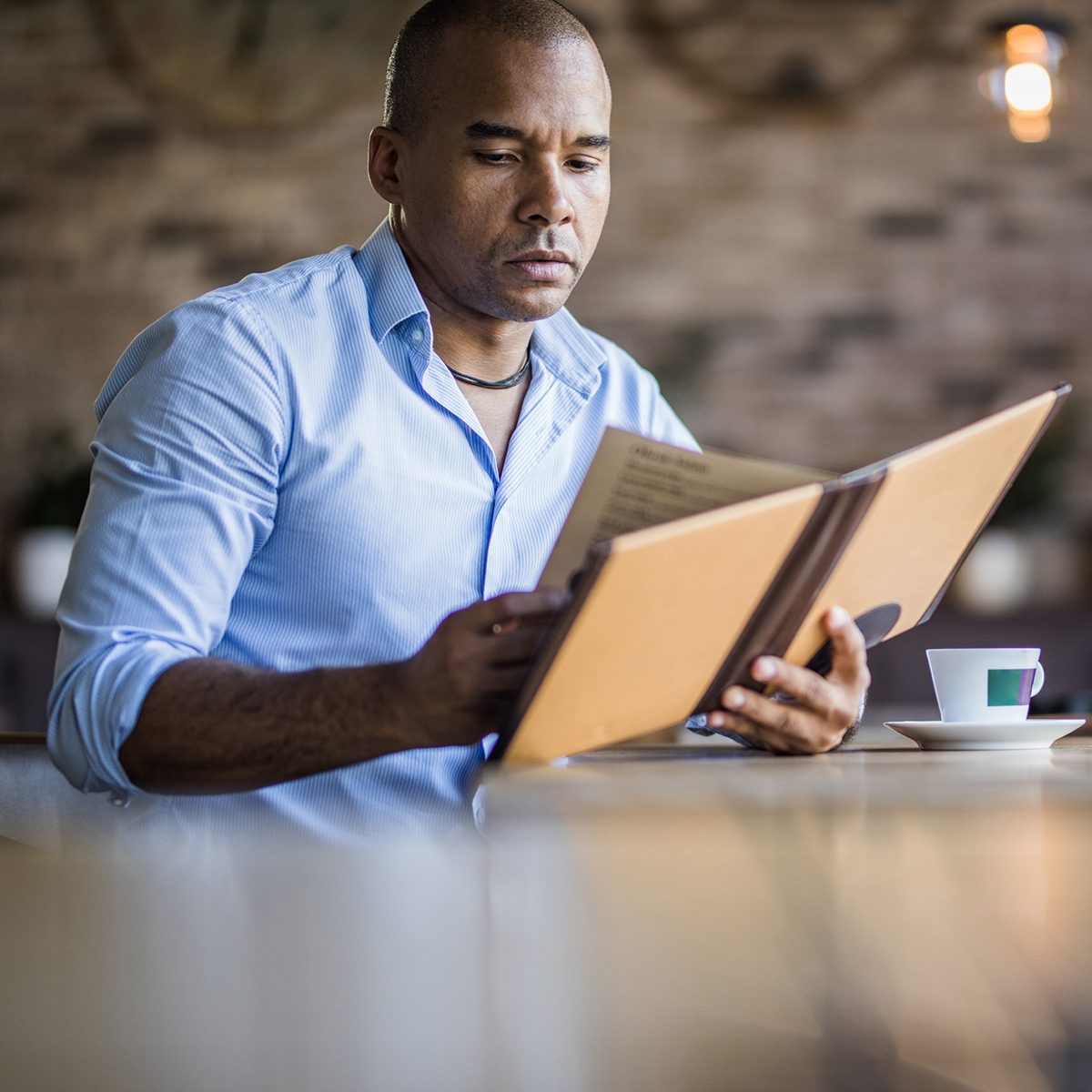 Mid adult African American businessman reading Menu in a cafe. Copy space.