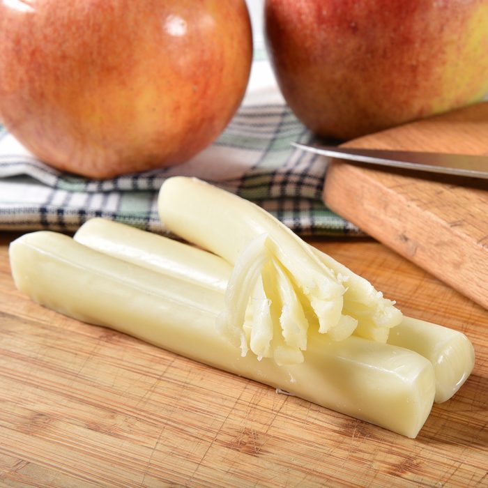Sticks of string cheese with Gaia apples on a cutting board