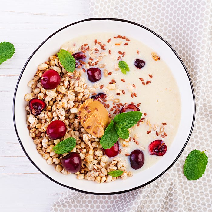 Breakfast. Bowl of homemade granola with banana mashed, peanut butter and fresh berries. Table setting. Healthy food. Top view.