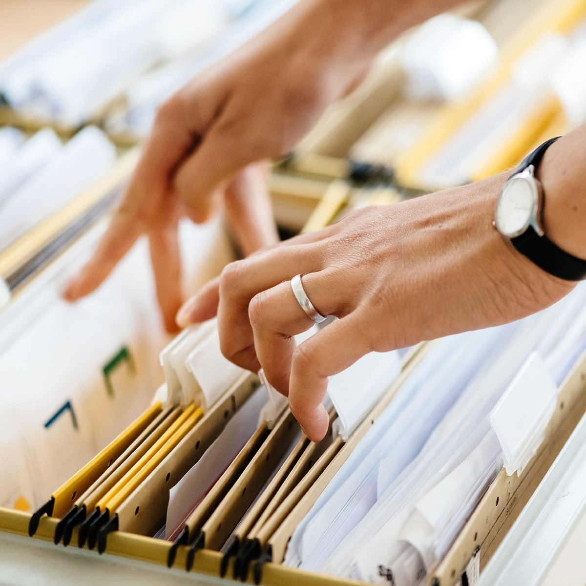 Close-up of hands searching in a file cabinet