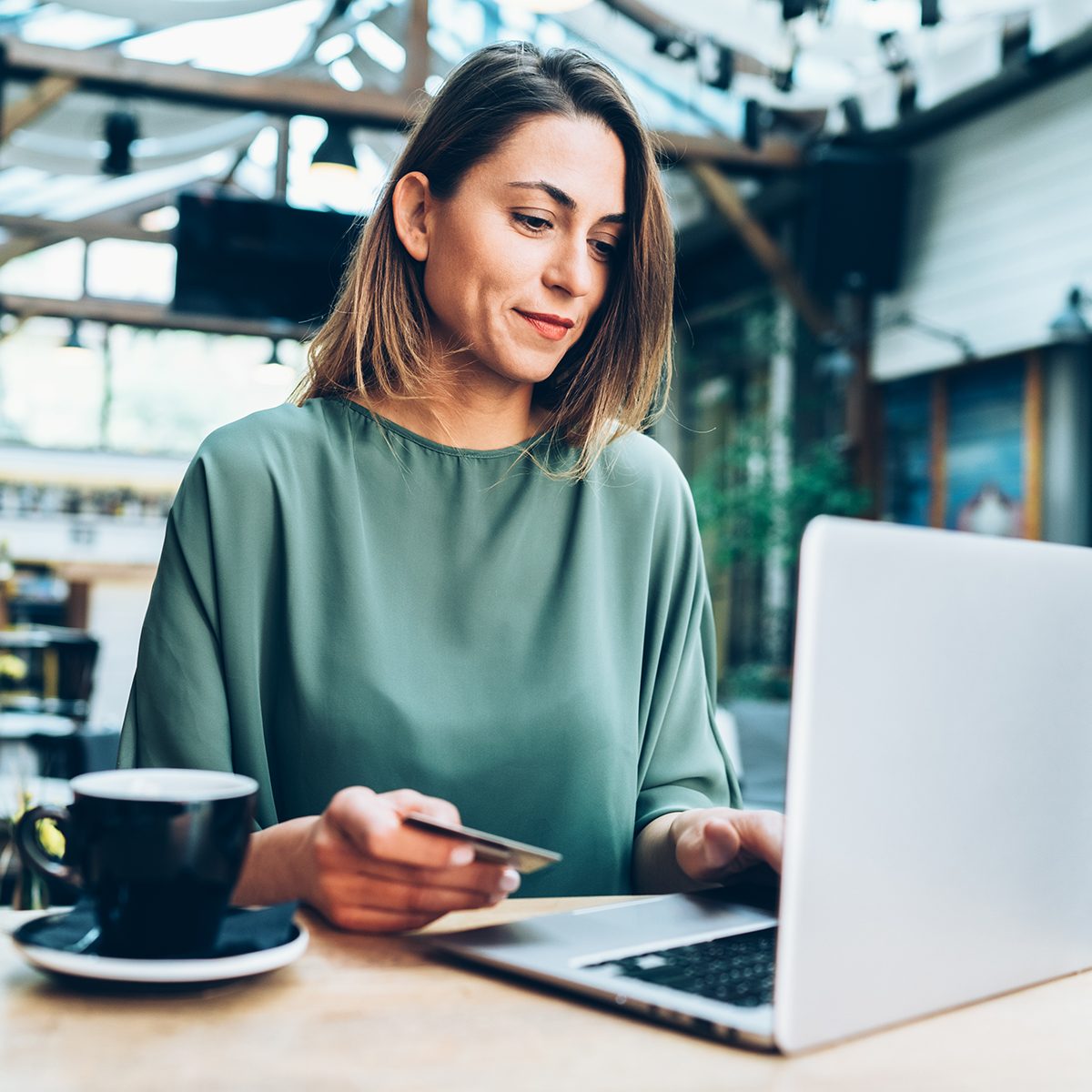 Young woman shopping online in cafe using lap top and credit card
