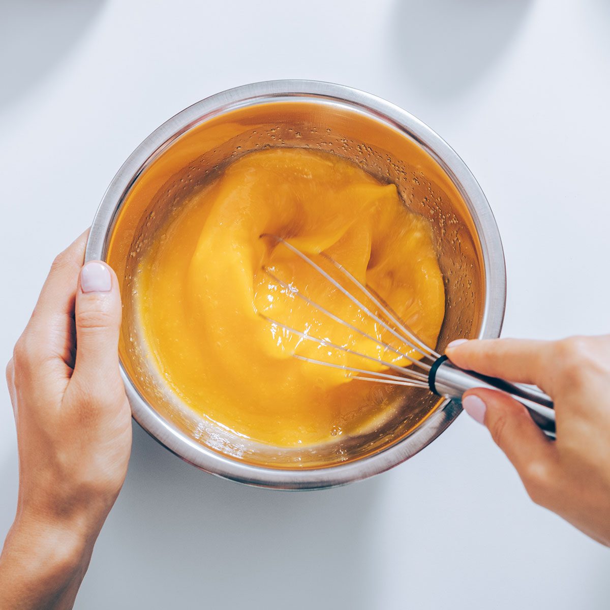 Close-up female hands whisk eggs for apple pie, view from above. Flat lay arrangement woman cooking fruit cake.