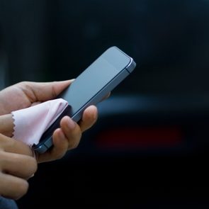 woman cleaning mobile smart phone with fabric