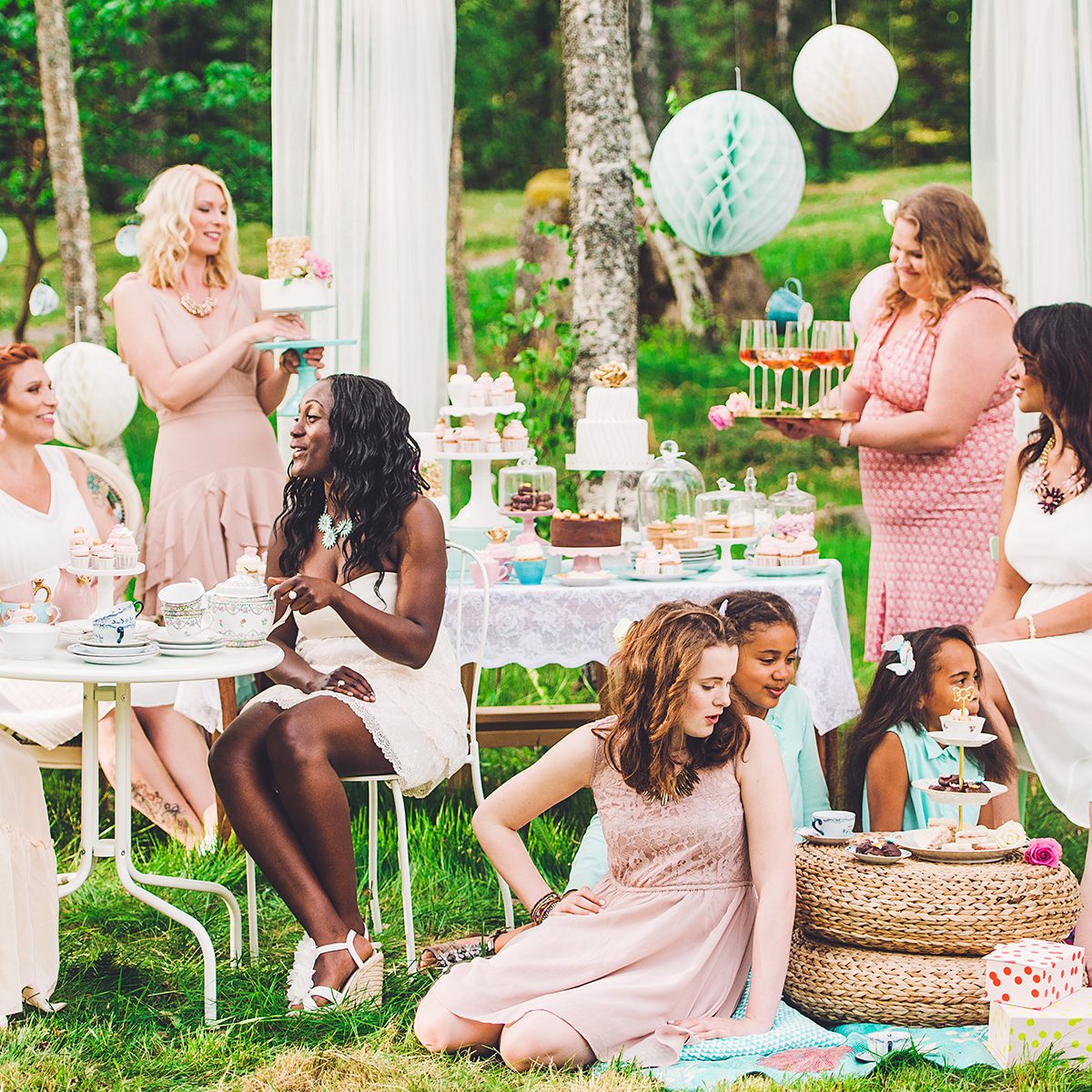 Eleven women having a garden party with dessert table