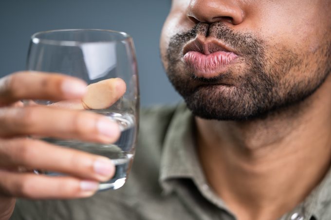Man Rinsing And Gargling With Water In Glass