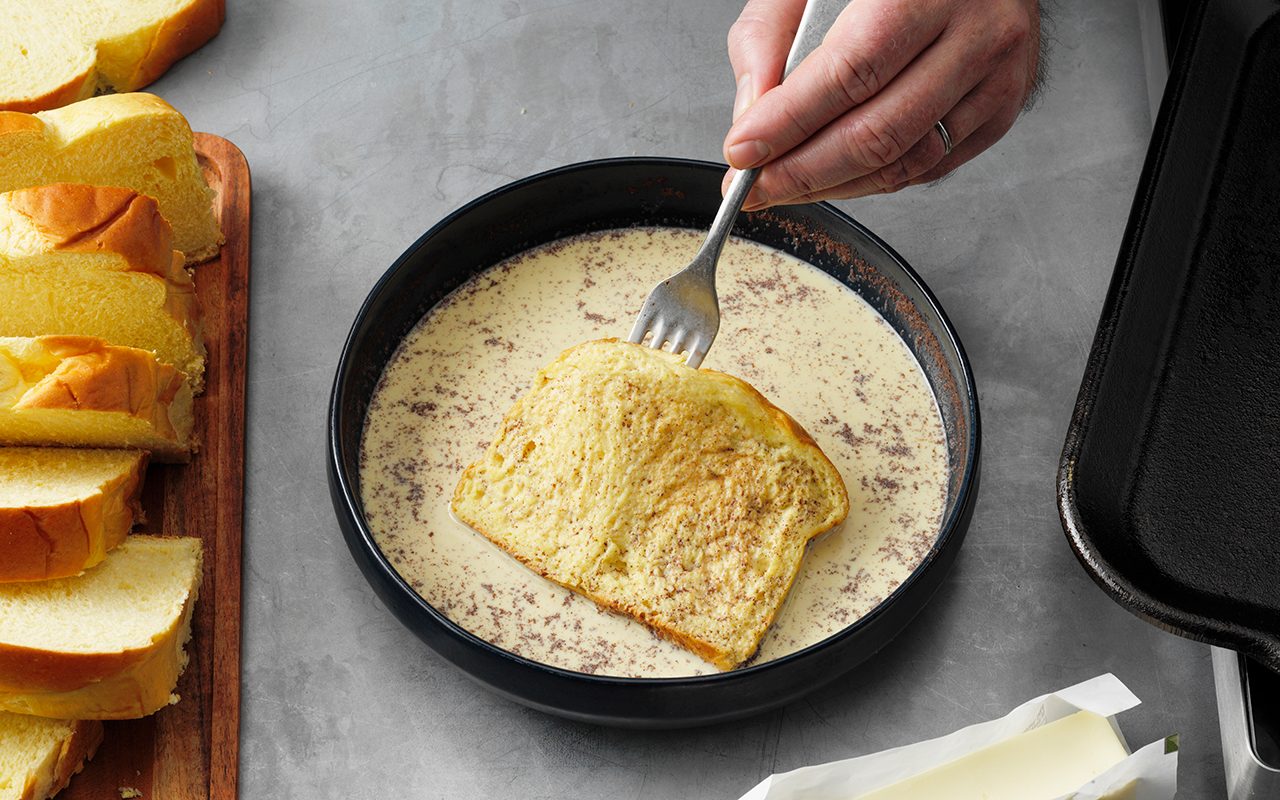 how to make french toast The Best French Toast; How to Step 4; flip and soak other side; half-and-half cream; egg yolks; brown sugar; vanilla extract; ground cinnamon; ground nutmeg; brioche bread; butter; maple syrup; fresh berries; whipped cream; confectioners' sugar; powder sugar; hands