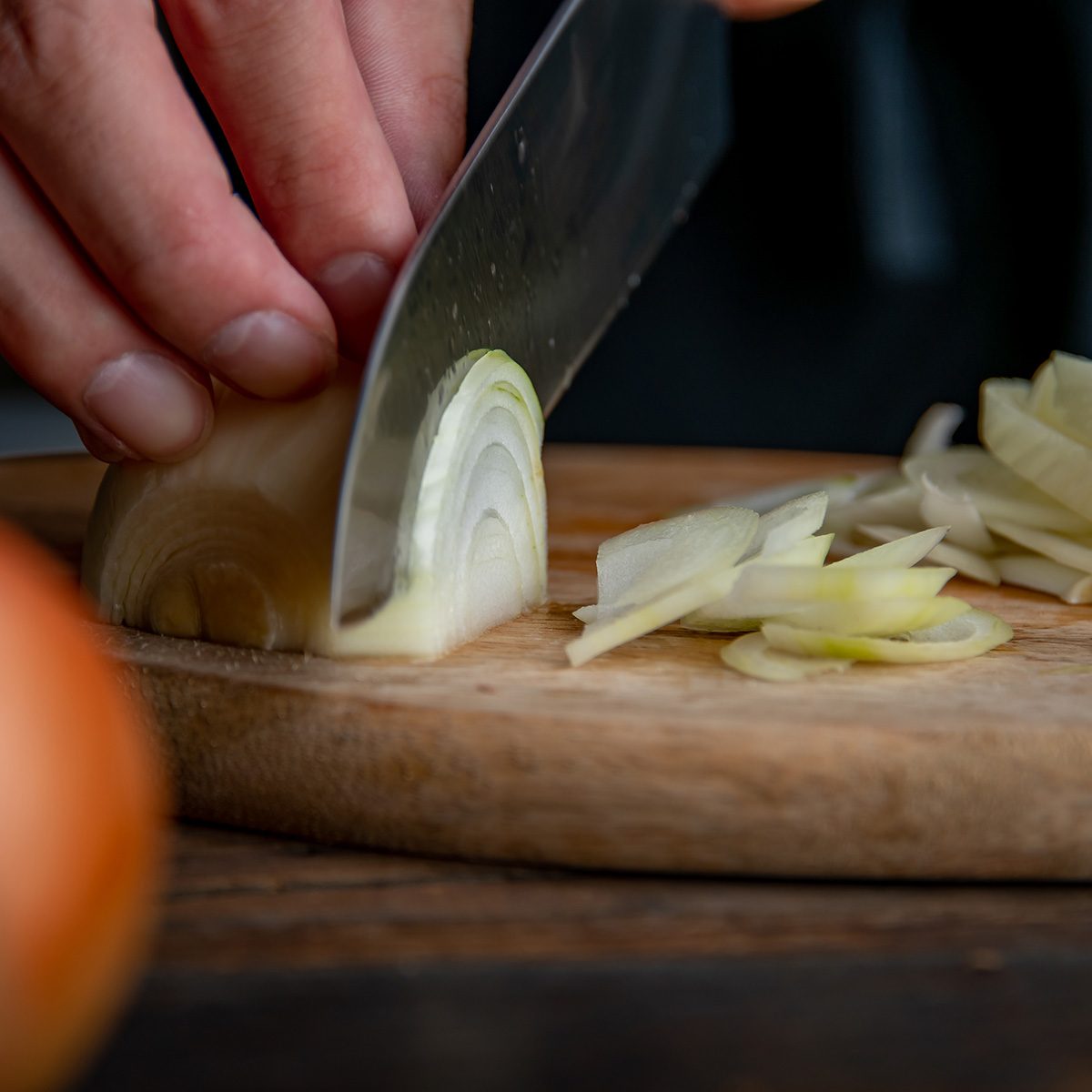 Slicing onion on cutting board in kitchen. Cooking image.
