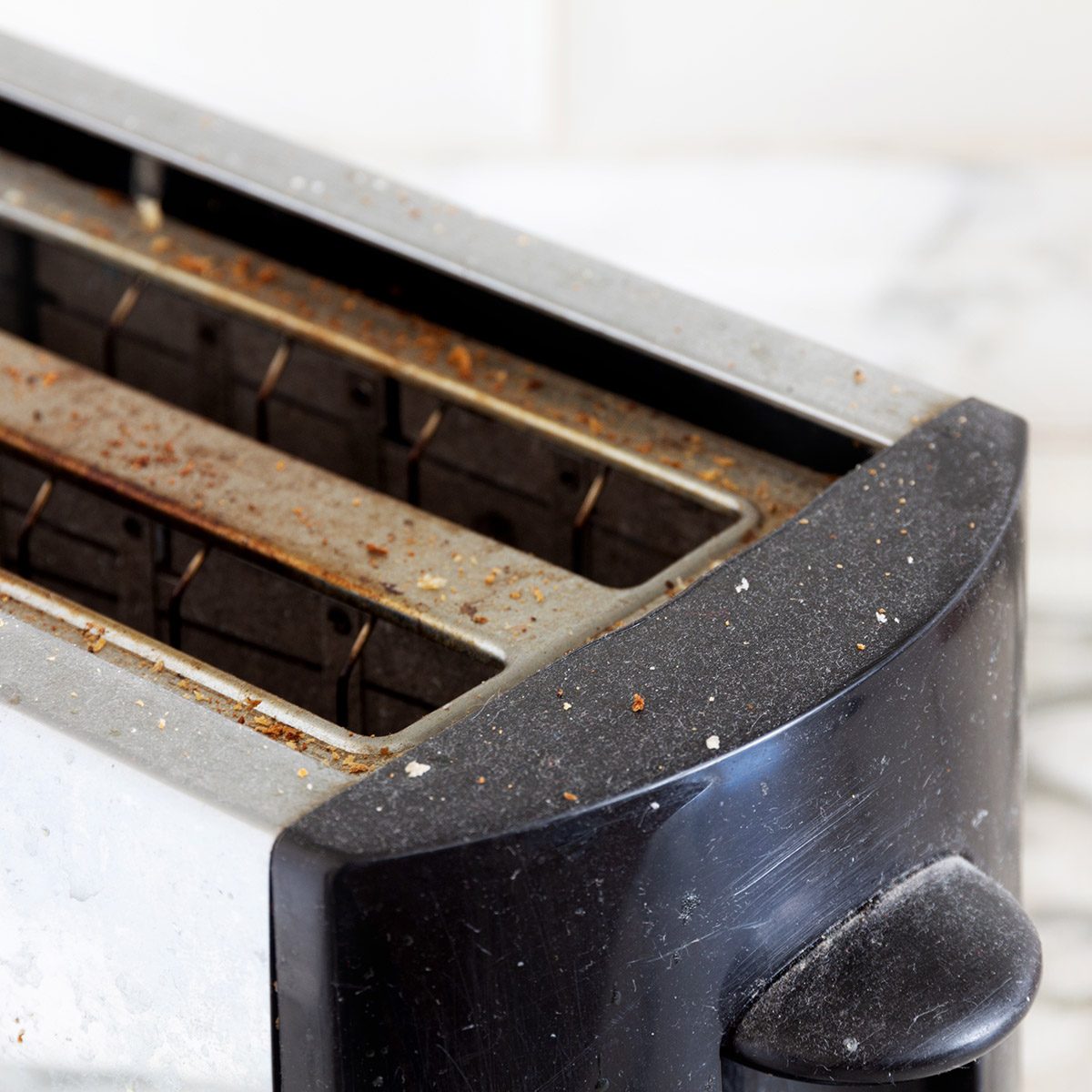 dirty kitchen toaster covered in dust and bread crumbs