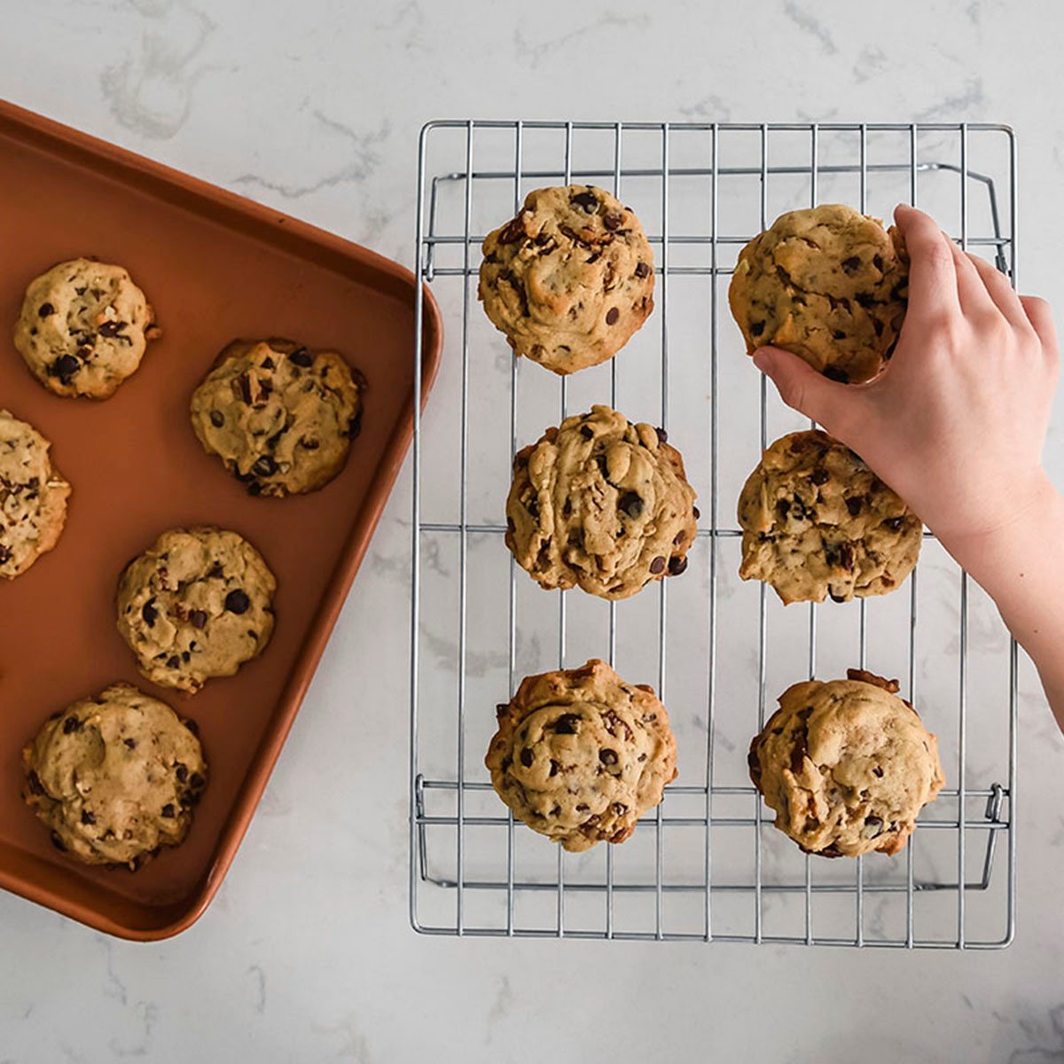 Hand of young child reaching to take a cookie off of a cooling rack