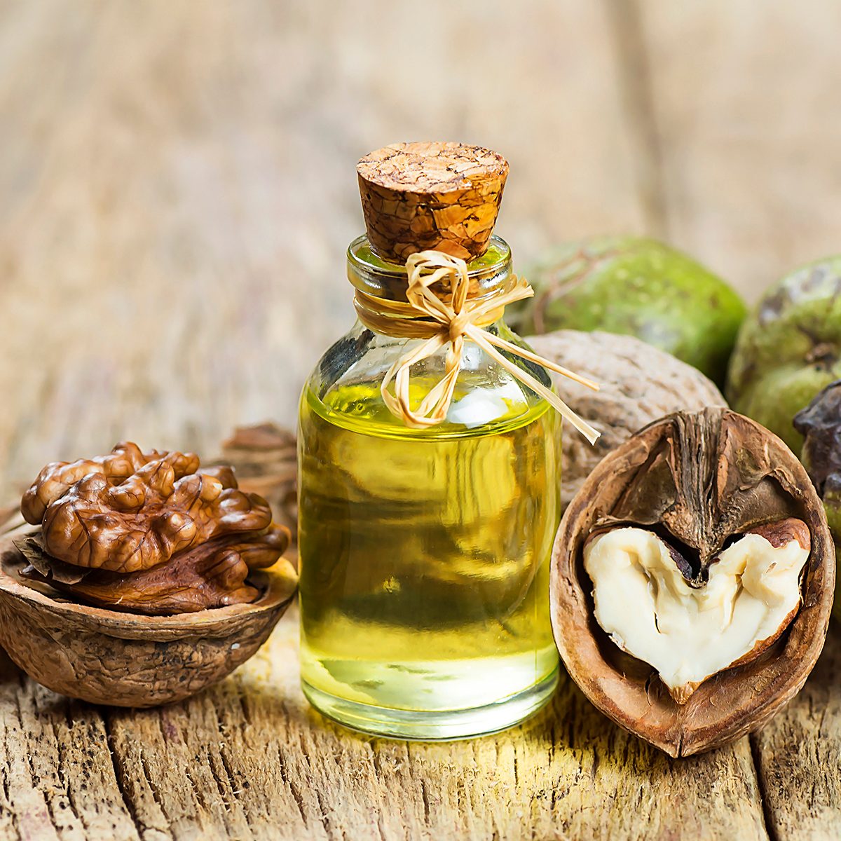 healthy oils Walnut oil in glass of bottle, whole big peeled walnut kernel with thin shell on wooden background. healthy food for brain. Fresh walnuts background nut concept
