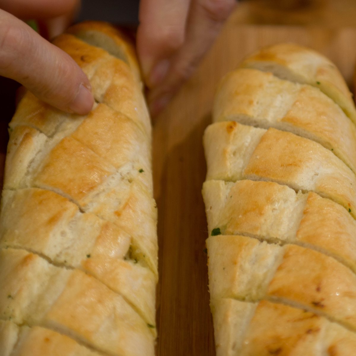types of french bread Whole garlic baguettes on a bread board being pulled apart by someone
