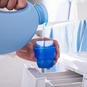 Person Pouring Detergent In Lid