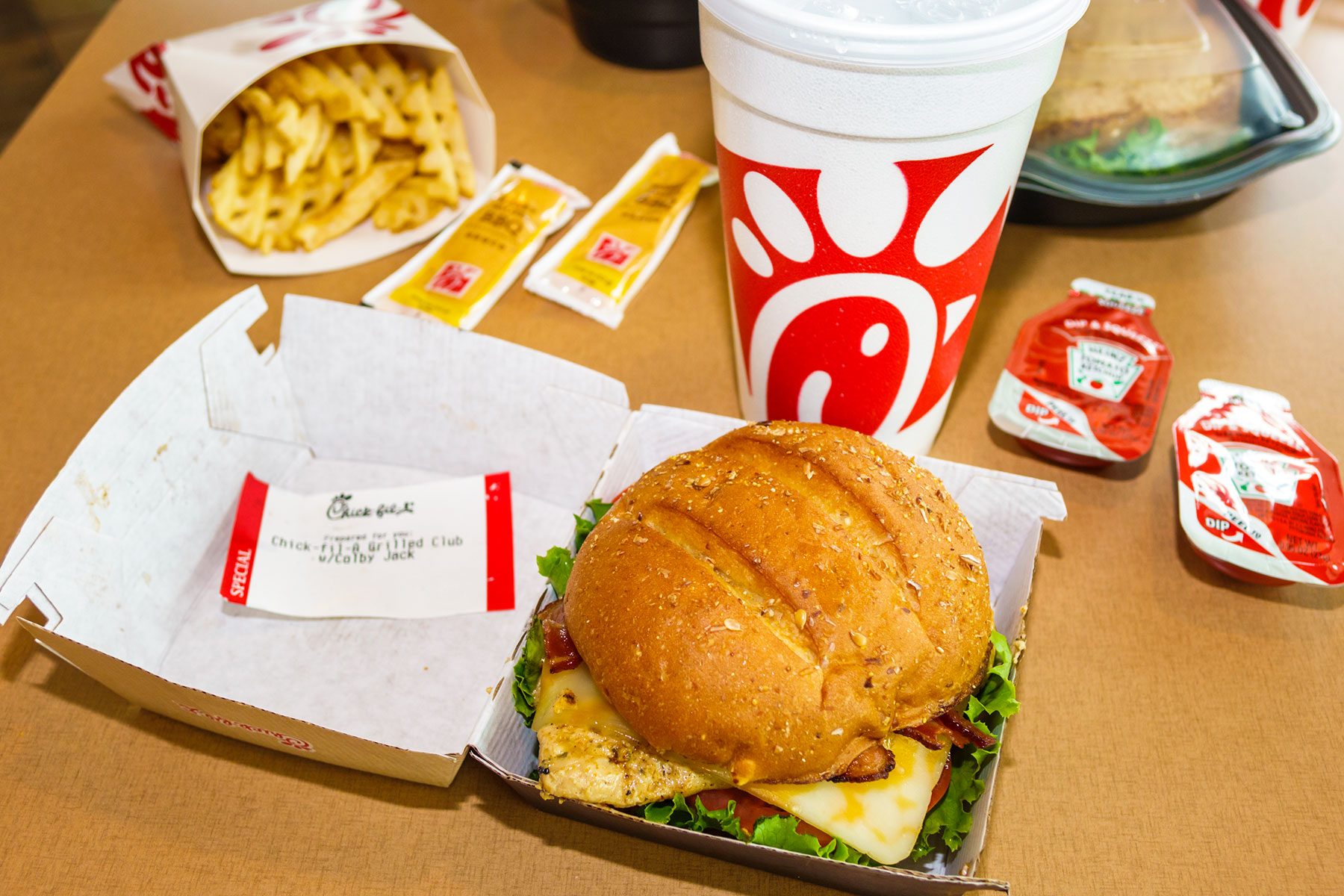 Grilled Chicken Sandwich Combo with fries drink and condiments at a table inside of a chick-fil-a franchise restaurant