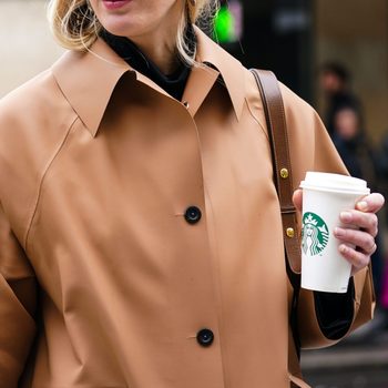 woman holding a starbucks cup while walking outside during autumn