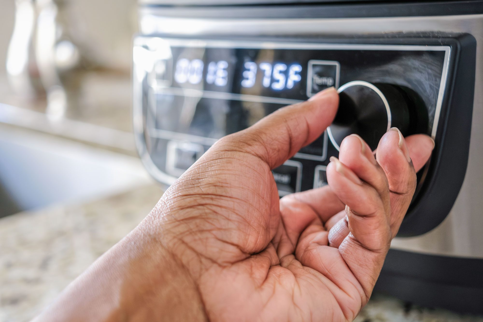 Woman Adjusting Temperature On Air Fryer