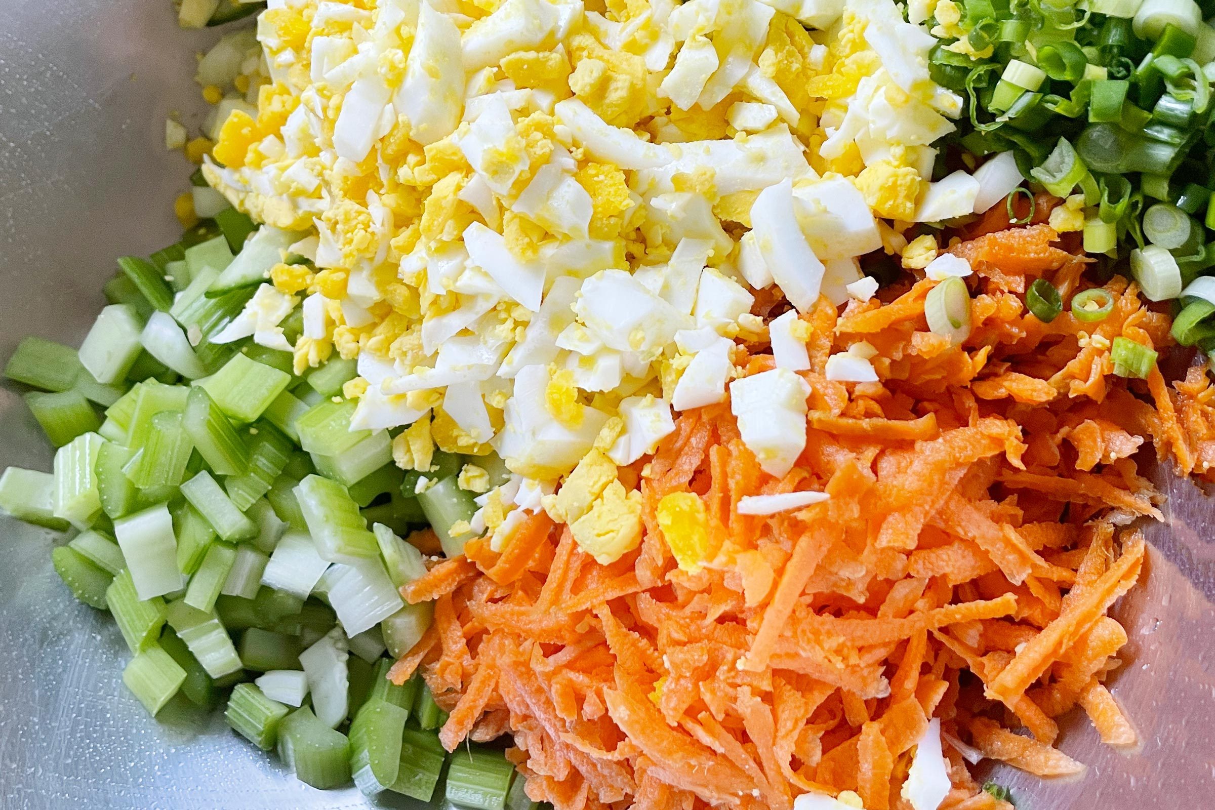 close up of chopped vegetables separated into piles in a bowl