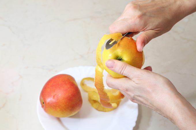 Woman peeling red apple in home kitchen