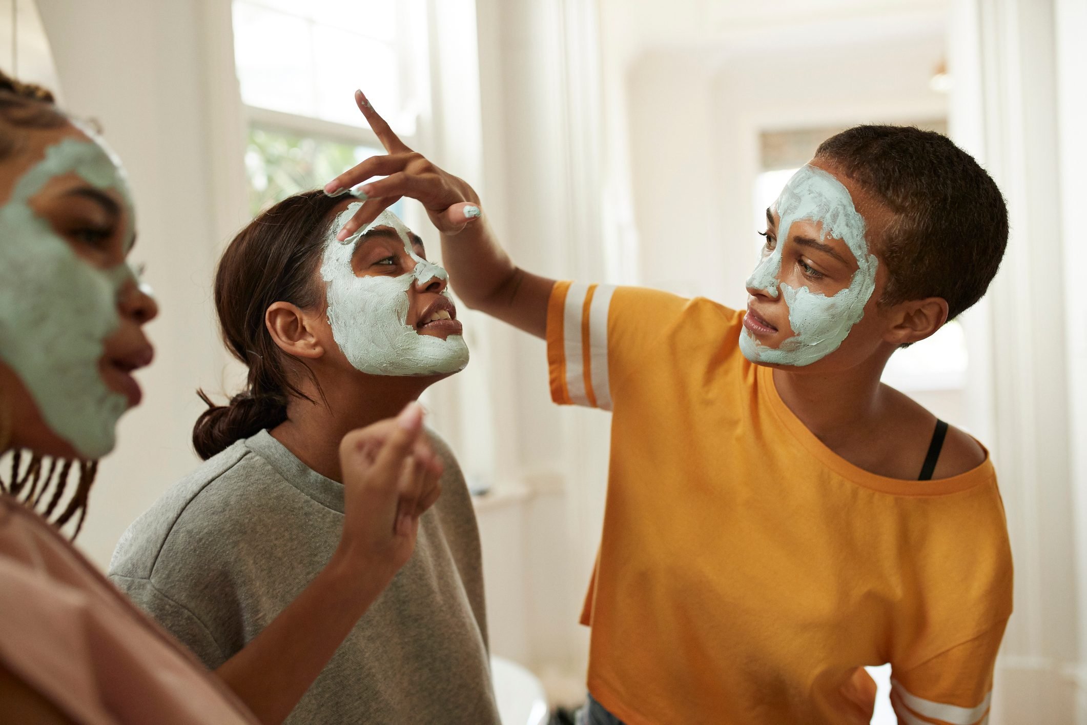 Woman looking at friend spreading cream with fingers