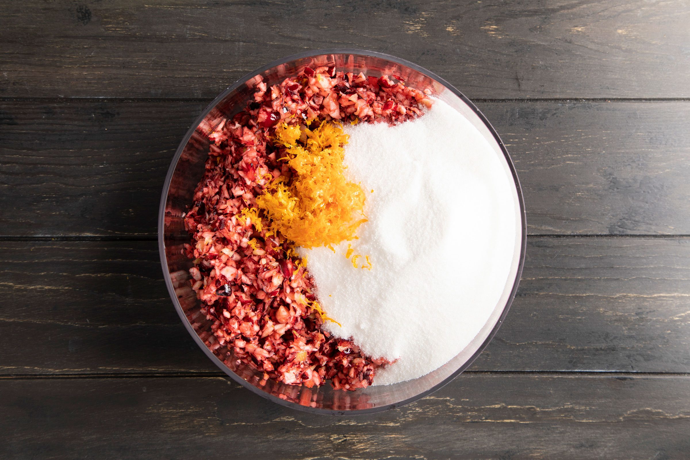 Cranberry Relish mixture in a glass bowl with orange zest and sugar