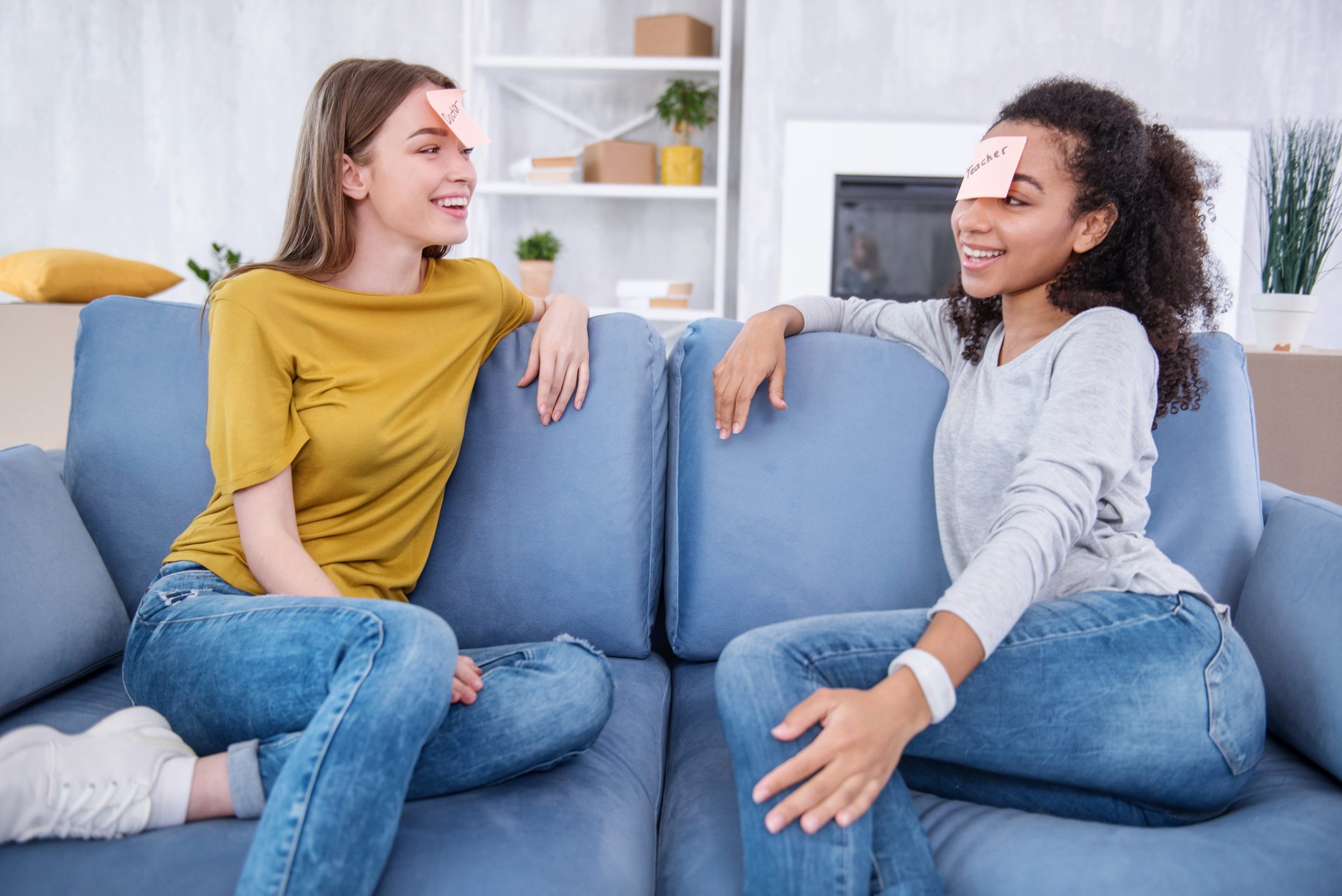 two girl friends playing heads up on a couch