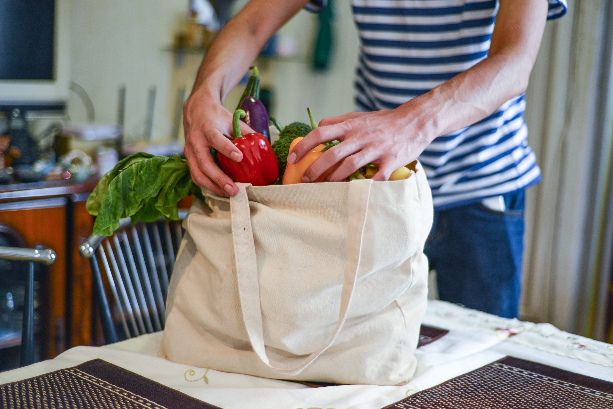 Asian man unpacking groceries at kitchen island