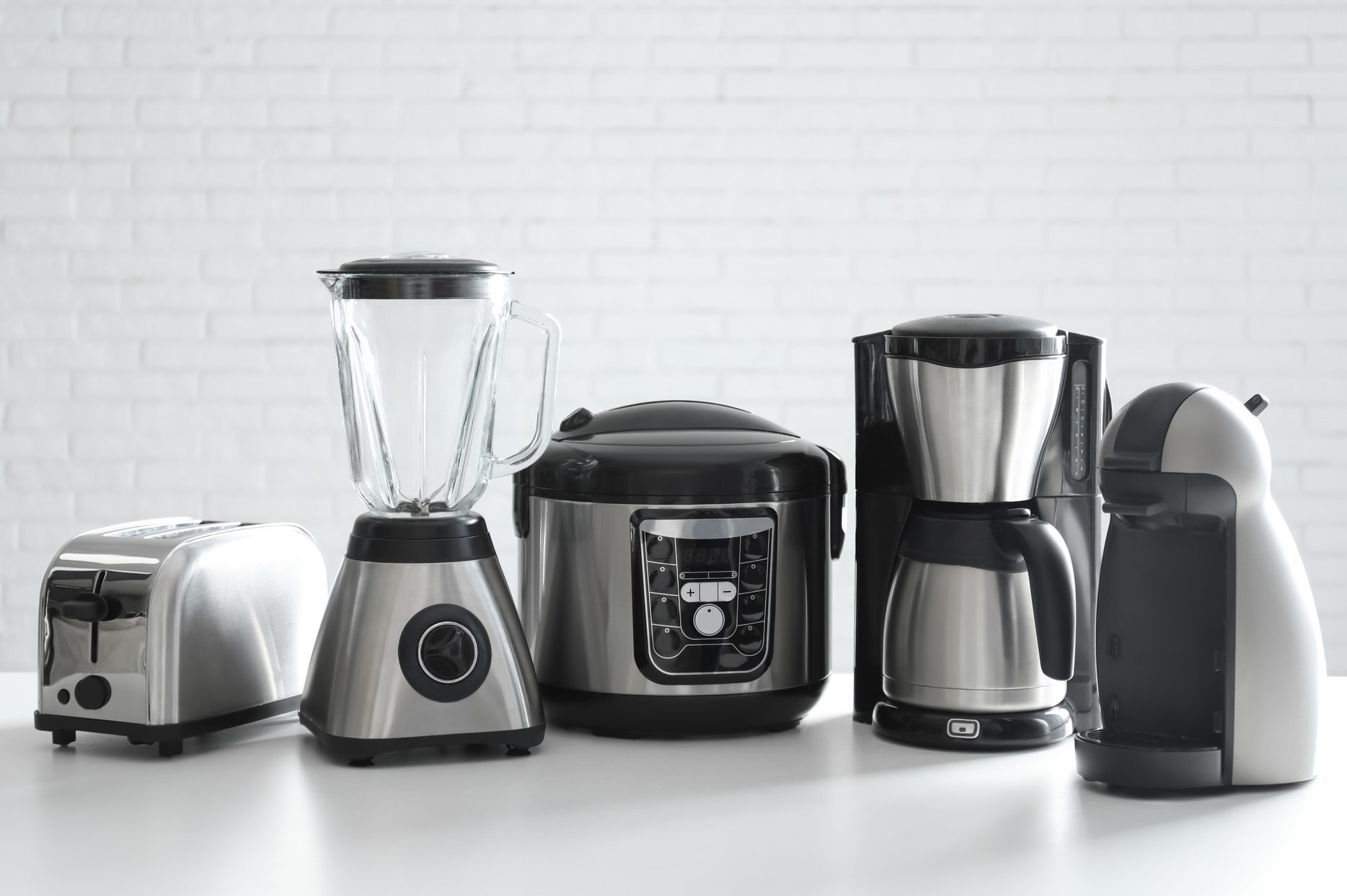 Set of modern home appliances on white table