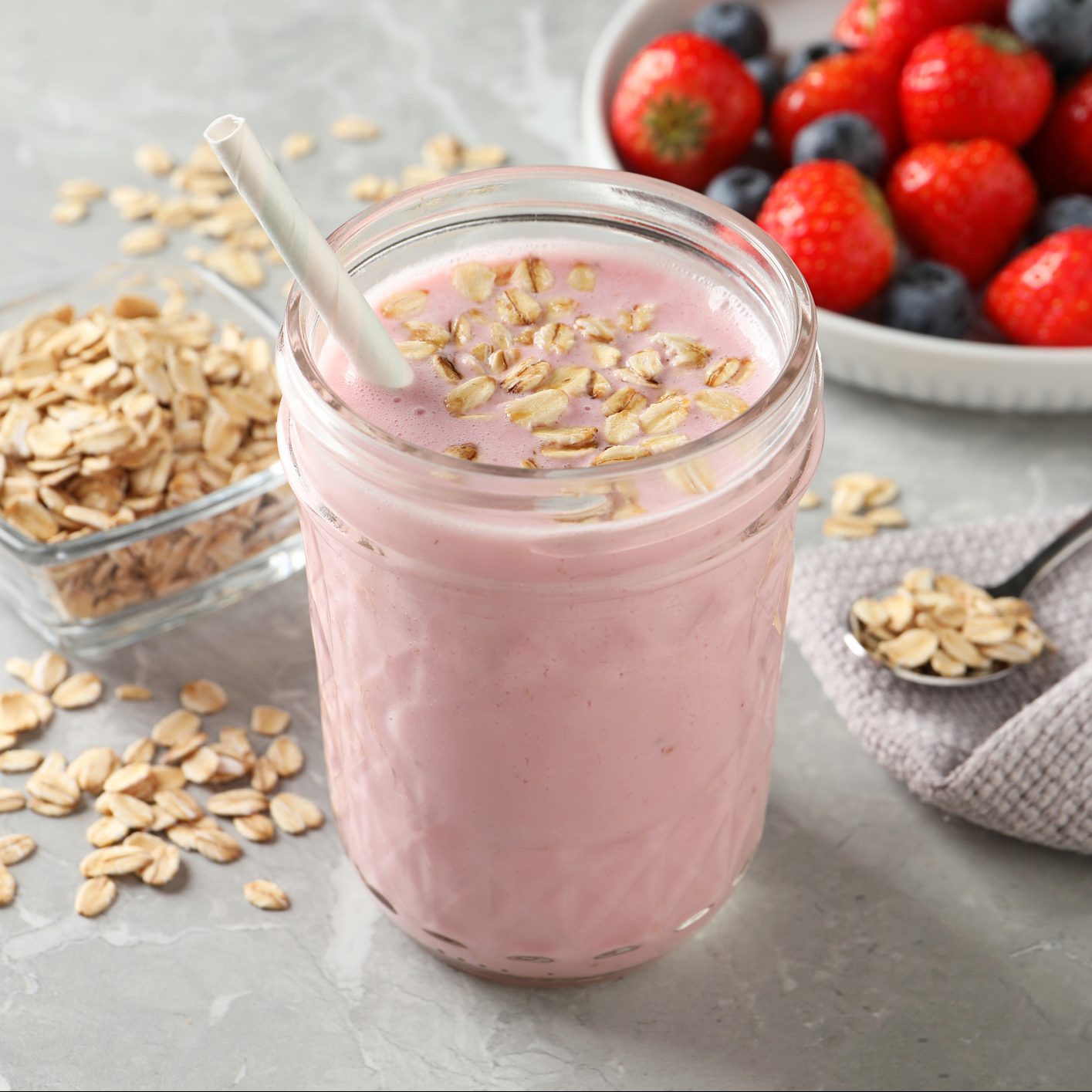 Jar of tasty berry oatmeal smoothie on grey table
