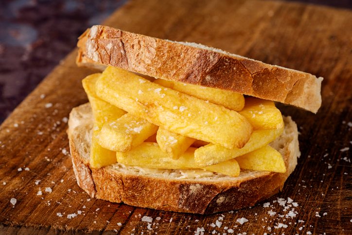 English Dish "Chip Butty" with french fries on buttered bread on a wooden countertop
