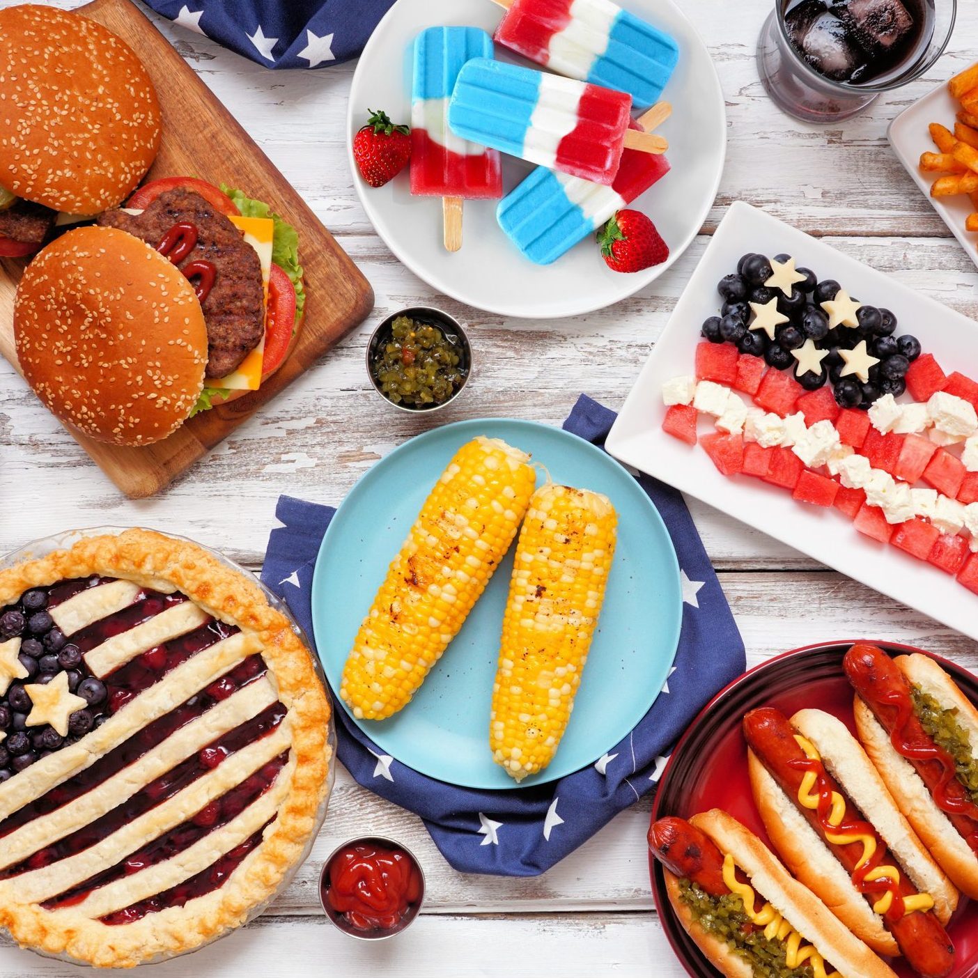 Fourth of July, American food. Above view table scene on white wood.