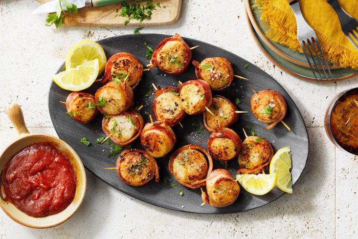 Bacon Wrapped Scallops on a black serving platter