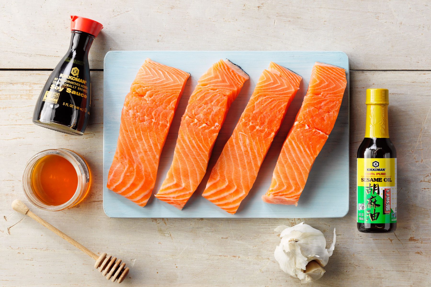 A Plate of Salmon With a Bottle of Sauce and Garlic